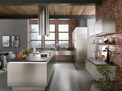 Durch die Ziegelwand kommt die INOX 216-Küche, im Look der Nachbildung von gebürstetem Stahl, ideal zur Geltung. Perfekt um so den den kühlen, klaren Industrial-Style in Ihrem Zuhause zu kreieren.