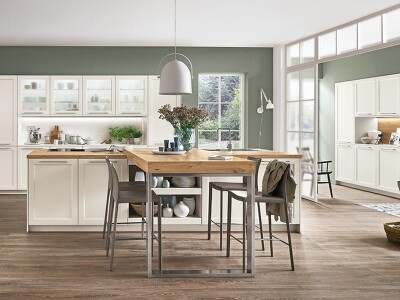 Weiße CASCADA 774 Landhausküche. Die Weiterführung des Dekors im Flur bringt ein einheitliches Gesamtbild. Tolle Ergänzung ist hier die Kücheninsel mit integriertem Tisch in Naturholz-Optik.