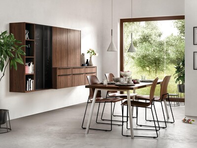 Auffallend stechen die Elemente der Wohnwand in Nussbaumnachbildung (RIVA 840) im Raum hervor. In farblicher Einheit mit Tisch und Stühlen wird ein wohnliches Ambiente geschaffen.